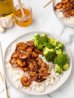 a plate with rice, broccoli and chicken on it next to chopsticks