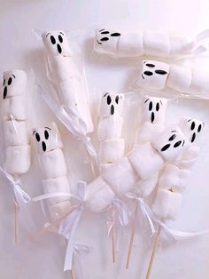 marshmallows wrapped in white paper and decorated with black eyes are arranged on sticks