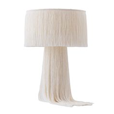 a lamp that is on top of a white table cloth with a light shade over it