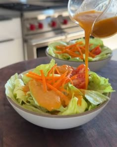 someone pouring dressing onto a salad in a bowl