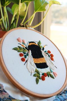 a bee embroidered onto a piece of cloth next to a potted plant