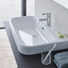 a white bathroom sink sitting on top of a counter next to a glass cup and toothbrush