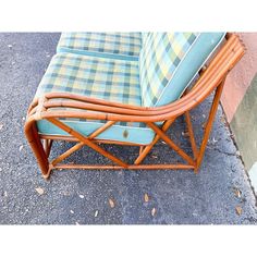 a blue and yellow plaid couch sitting on top of a cement floor next to a wall