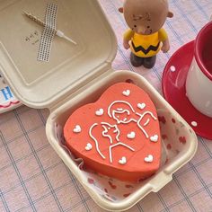 a heart shaped cake sitting in a container next to a cup