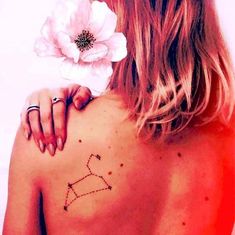 a woman with a flower in her hair and a tattoo on her back is looking at the sky