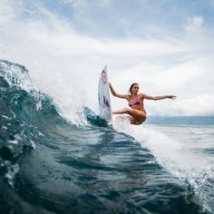 a woman riding a wave on top of a surfboard