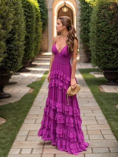 a woman in a long purple dress is standing on a brick walkway and looking off into the distance