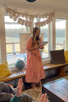 a woman standing in front of a window holding a piece of paper while people look on