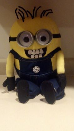 a small yellow and black toy sitting on top of a counter next to a white wall