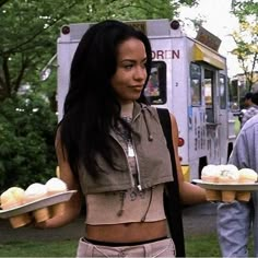 a woman holding two trays of cupcakes in front of an ice cream truck