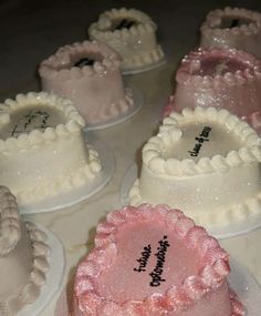 there are many small cakes with writing on the top one is white and has pink frosting