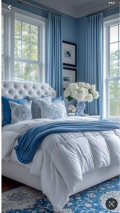 a bedroom with blue walls and white bedding, flowers in a vase on the headboard