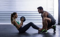 a man and woman doing squats on the floor with a medicine ball in front of them