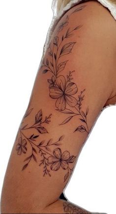 a woman's arm with flowers and leaves tattooed on the upper half of her arm