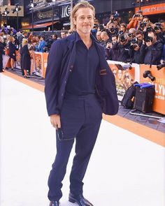 a man standing in front of a crowd wearing a suit and tie with his hands in his pockets