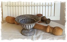 an old fashioned mortar bowl and two wooden mallets on a white tablecloth with a fence in the background