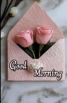 two pink roses are in an envelope with the words good morning on it and some white flowers