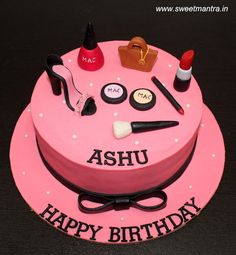 a pink birthday cake with makeup, lipstick and shoes on it that says ashu happy birthday