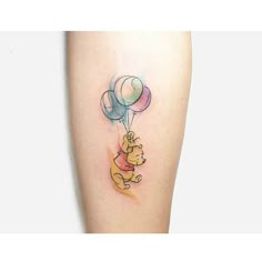 winnie the pooh tattoo with balloons on her leg and an elephant holding onto it