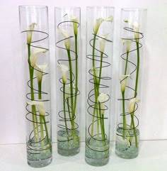 four clear vases with white flowers in them