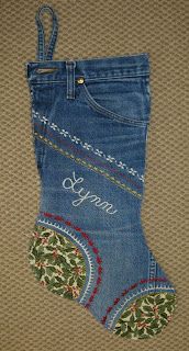 a pair of blue jeans with the words happy on them are sitting next to an embroidered christmas stocking