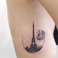 a woman's thigh with the eiffel tower and moon tattoo on it