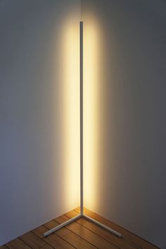 the light is shining through two poles in an empty room with wood flooring and white walls