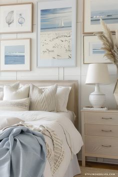 a bedroom with white walls and pictures on the wall above the bed, along with two lamps