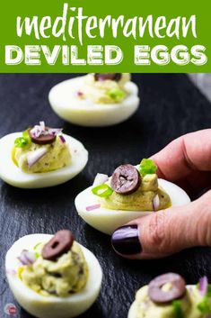 deviled eggs with mushrooms and other toppings on a black surface, one being held by a woman's hand