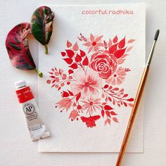 a card with red flowers on it next to a paintbrush and some other items