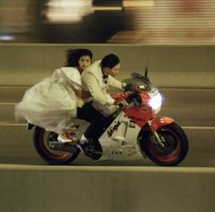 a man and woman riding on the back of a motorcycle