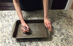 a person standing over a pan with a knife in it