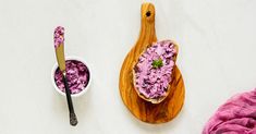 a wooden spoon sitting next to a bowl filled with purple food on top of a table