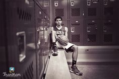 a man sitting on a bench with a basketball in his hand and lockers behind him