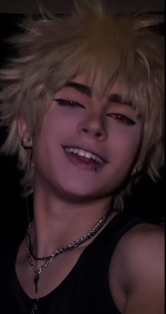 a young man with blonde hair and piercings on his face smiling at the camera