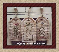 three hand embroidered christmas tags hanging from a window sill with the words design by primitive stitches on them