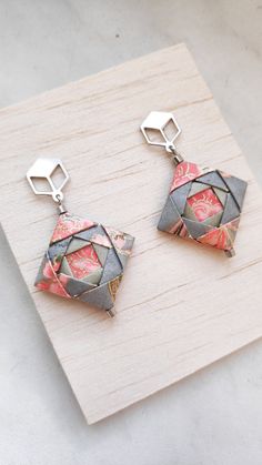 two origami earrings on top of a wooden board