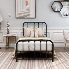 a bedroom with a metal bed frame, white walls and rugs on the floor