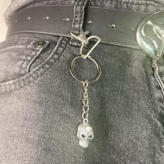 a person wearing jeans with a skull keychain on their waist and an eyeball in the back pocket