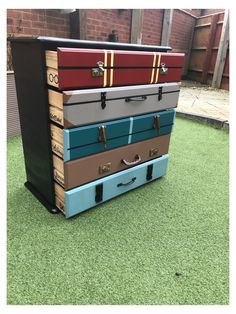 four suitcases stacked on top of each other in front of a brick wall and green grass