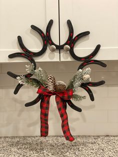 a reindeer antlers decoration hanging on the kitchen counter top with pine cones and evergreens