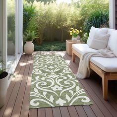 a green and white rug sitting on top of a wooden floor next to a couch