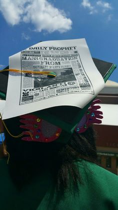 a person wearing a graduation cap and holding up a paper with an image on it