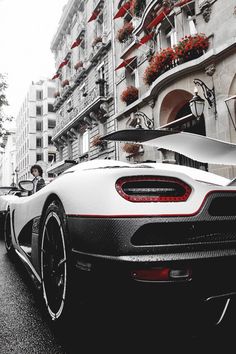 a white and black sports car parked in front of a tall building on a city street