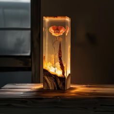 a glass vase with flowers in it sitting on a wooden table next to a window