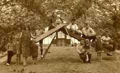 an old black and white photo of children playing on a playground structure in the woods