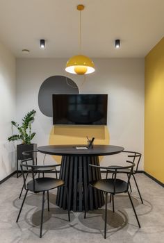 a round table with four chairs and a flat screen tv mounted on the wall behind it