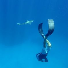 a man is diving in the blue water with a mask on his face and a shark behind him