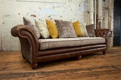 a brown leather couch sitting on top of a wooden floor next to a white wall