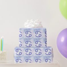 two wrapped presents sitting on top of a table next to balloons and cake with candles